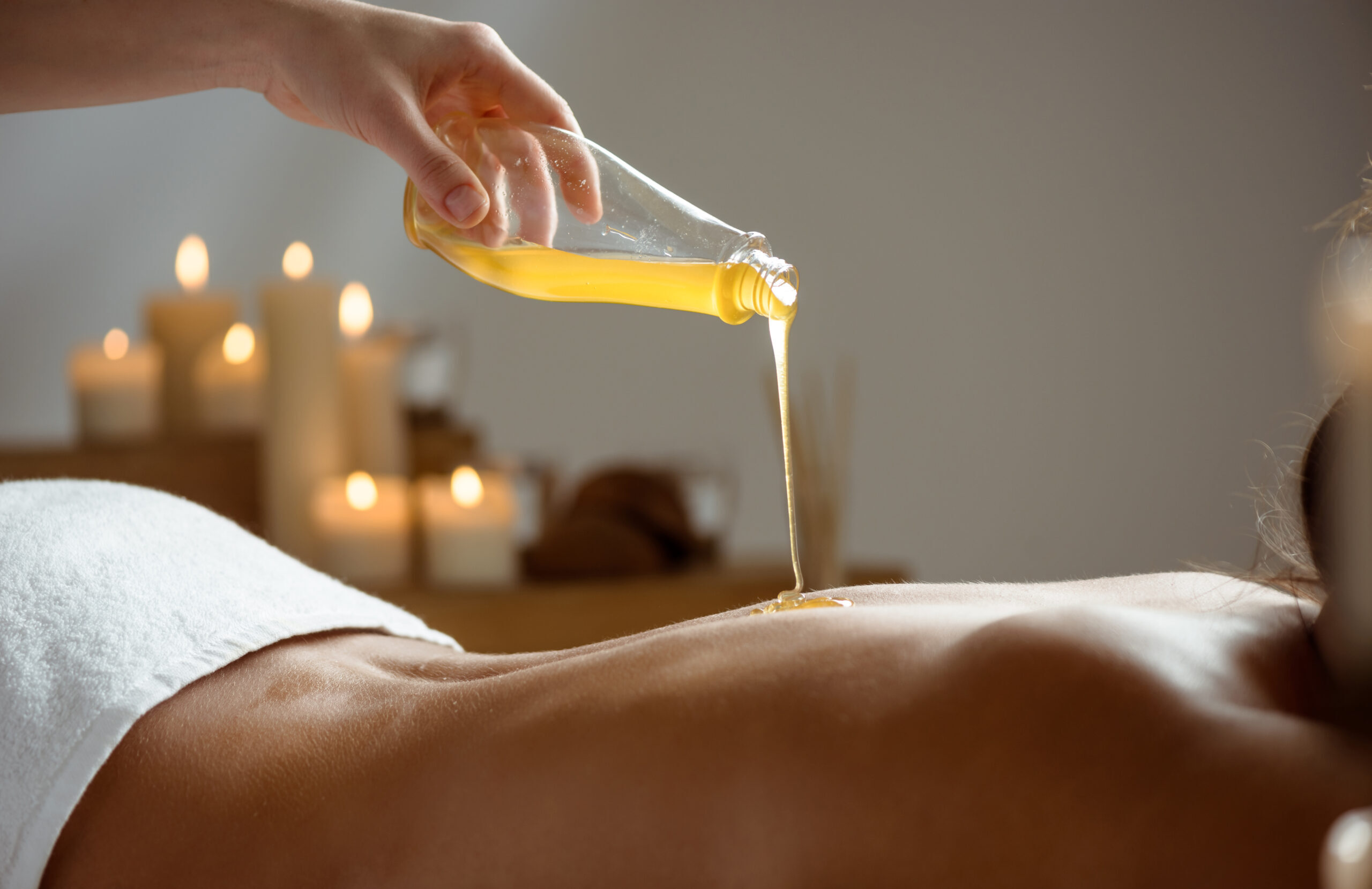 Honey pouring on girl's naked back in spa salon. Copy space.